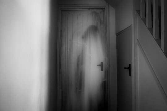 A ghostly, blurred, hooded figure. standing in a corridor.