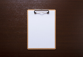 Clipboard with white paper on a wooden background