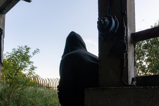 A hooded man standing in the entrance of a ruined building.