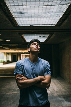 Thoughtful young man with arms crossed standing in basement