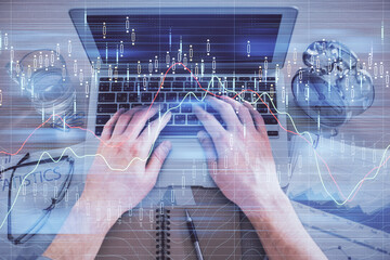 Multi exposure of man's hands typing over computer keyboard and forex graph hologram drawing. Top view. Financial markets concept.