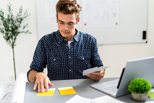 Man choosing yellow shade while sitting by desk at office
