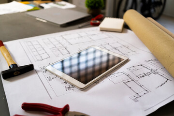 Smart phone and hammer lying on architectural blueprint