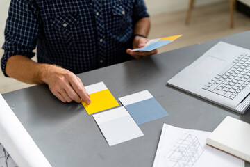 Architect choosing color swatch while sitting by desk at office