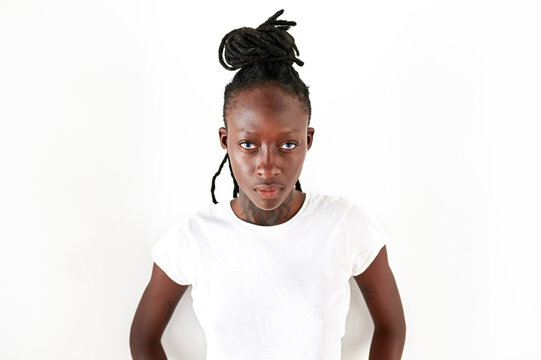 Serious young woman with locs standing against white background