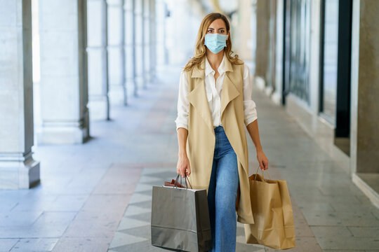 Woman with face mask carrying bag while walking at store lobby in city