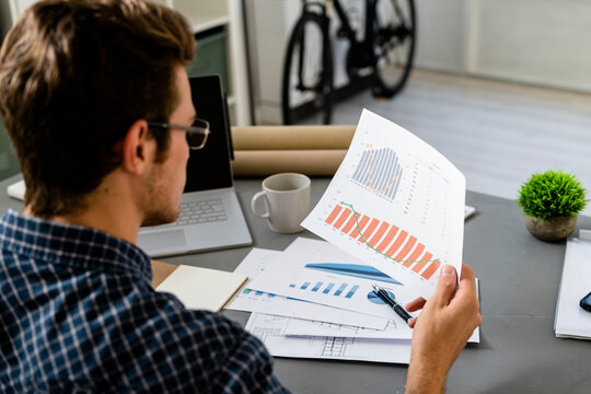 Architect analyzing graph while sitting by desk at office