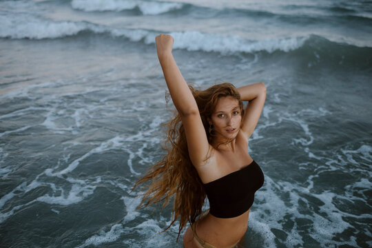 Beautiful woman standing in sea during sunset