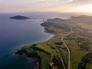 Russia, Primorsky Krai, Zarubino, Aerial view of coastal roads stretching along shore of Sea of Japan at dusk