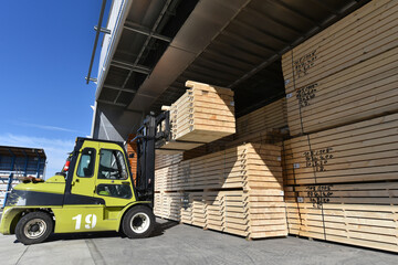 Forklift stacking planks inside lumberyard warehouse