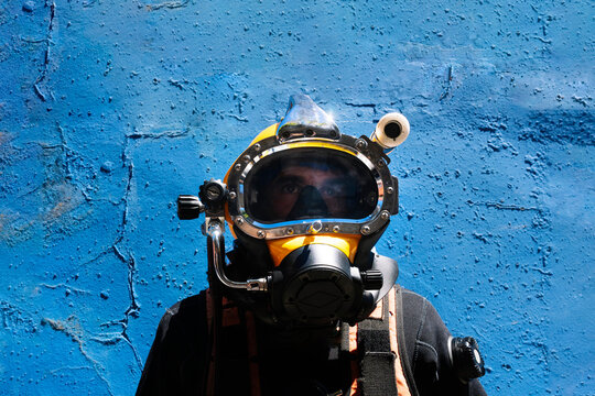 Close-up of male instructor wearing diving suit standing against blue wall