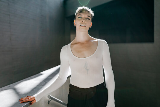 Non-binary young man wearing white leotard standing in basement