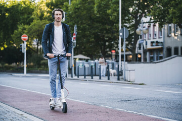 Man listening music while riding electric push scooter in city