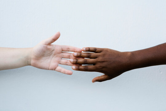 Friends holding hand against white wall