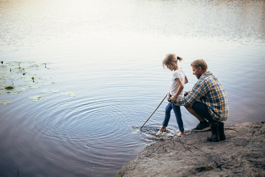Father holding daughter during fishing by lake