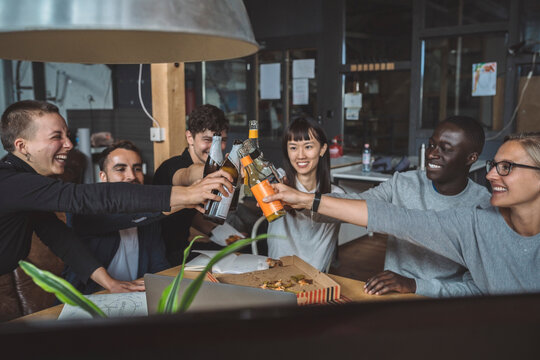 Smiling coworkers toasting beer at workplace