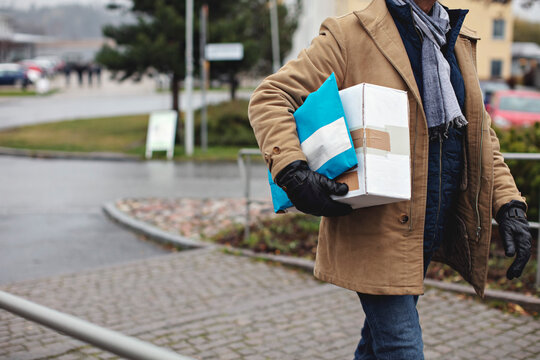 Midsection of senior man with package walking by sidewalk during winter