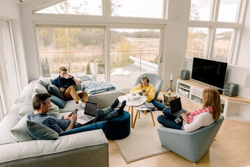 High angle view of family using technology while sitting in living room