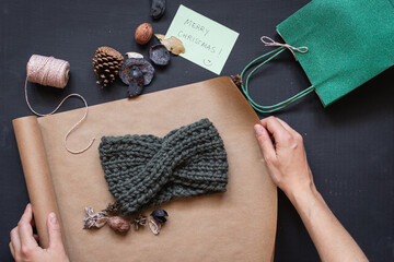 Flat lay of a handmade headband being wrapped in brown paper and a card wishing marry christmas