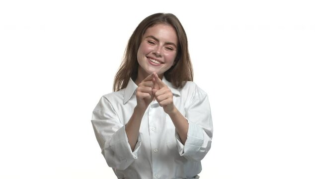Attractive caucasian business woman in white collar shirt, shaping heart sign in the air and smiling, like or love something, standing over studio background
