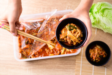 Korean food, Kimchi cabbage in a bowl holding by hand and eating with chopsticks, Top view