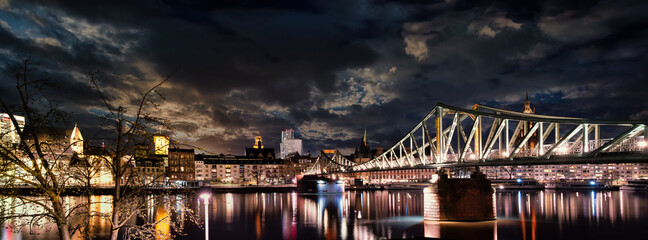 Night view to the Eisenerner Steg bridge and the illuminated cityscape of Frankfurt
