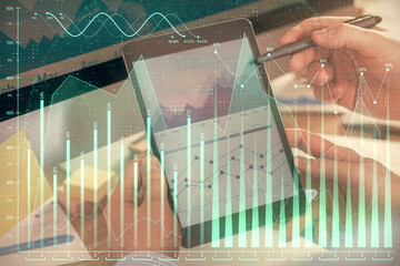 Double exposure of man's hands holding and using a phone and financial chart drawing. Market analysis concept.