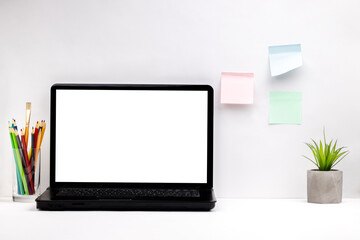 white home office with blank laptop mockup, sticky notes at wall and some stationery on a tabletop. light minimal concept. business desk background