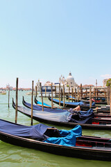 Fototapeta na wymiar Gondola boats lined up in Venice, Italy with dome in background. No people, space for copy.