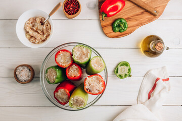 Pepper stuffed with chicken minced meat and rice in a glass bowl on a white wooden background.