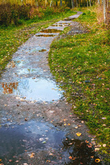 Bad way. Wet, with many puddles, dirty alley in the park in autumn after rain