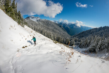 Fototapeta na wymiar Winter sport activity. Adventurous woman hiking through deep snow in the mountains.