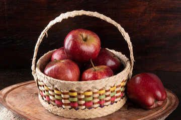 Red apples in basket with wooden background