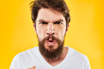 emotional bearded man gesturing with hands aggression discontent close-up yellow background