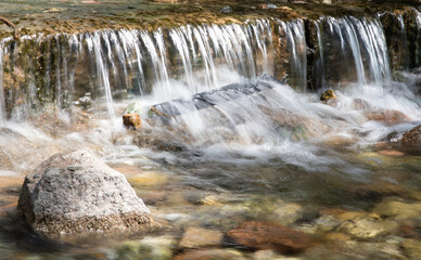 Fototapeta premium Small waterfall flowing in the summer mountain