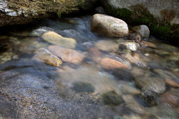 Slow shot of the stream flowing in the mountains outdoors in summer