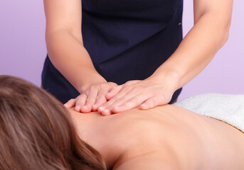 Fototapeta na wymiar Hands of masseur doing massage of spine in a salon