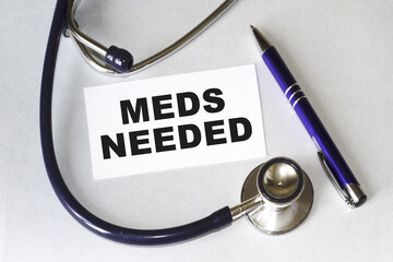 MEDS NEEDED. stethoscope on the table with a letterhead and a pen. CARD showing medical information, diagnosis, isolated on a white background, close-up, cropped view.A medical concept.