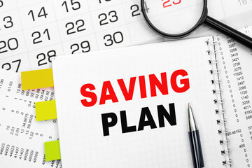 Notepad with text SAVING PLAN on the white background with financial documents and office supplies. Business concept.