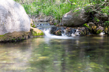 Naklejka na ściany i meble Slowly shoot a small pool of water flowing in the mountains