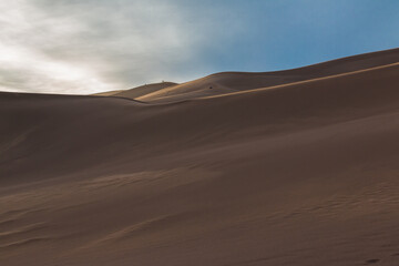 Fototapeta na wymiar Climbers Watching Sunset on The Dune Field of Great Sand Dunes National Park, Colorado, USA