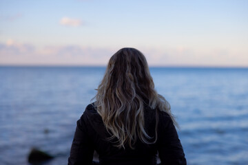 Woman looking thoughtful into lake Erie.  - obrazy, fototapety, plakaty