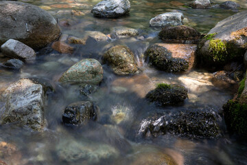 Slow shot of the clear stream flowing in the outdoor mountain