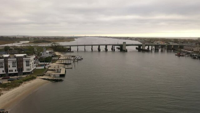 An Aerial Shot Over The East Rockaway Inlet In NY. The Drone Dolly In To The Nassau Expressway Drawbridge On A Cloudy Morning With No People In View, Only Two Cars Driving Over The Bridge. It Is Calm.