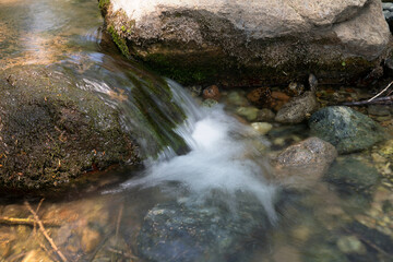 Naklejka na ściany i meble Slow shot of the stream flowing in the mountains outdoors in summer