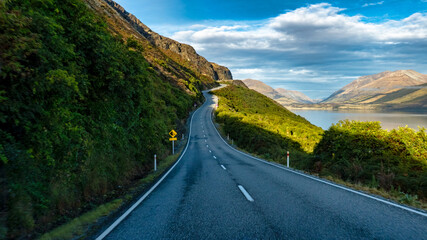 Long and winding highway on the edge of the stunning lake Wakatipu near Queenstown bordered by the Southern Alps