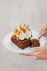 modelo femenina sosteniendo un plato de pastel de brownie con dulce de leche y merengue italiano