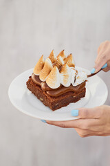 modelo femenina sosteniendo un plato de pastel de brownie con dulce de leche y merengue italiano