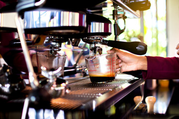 Fototapeta na wymiar Staff are extracting coffee from a professional coffee machine at the coffee shop in the morning.