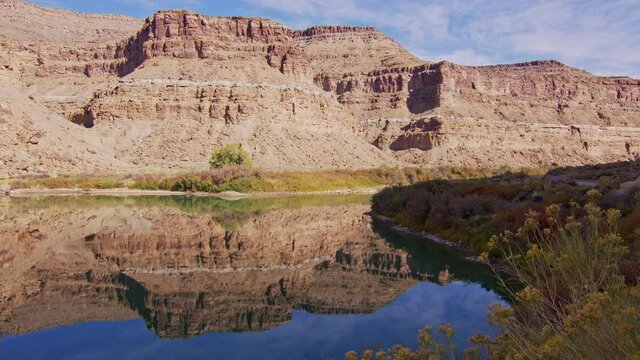 Reflection of desert cliffs in the glassy water of the Green River in Utah during Fall.